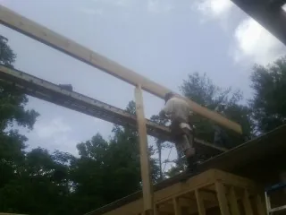 Carpenter setting a ridge beam over a new addition frame — Ice Dam Removal by Roofing Brothers in Buxton